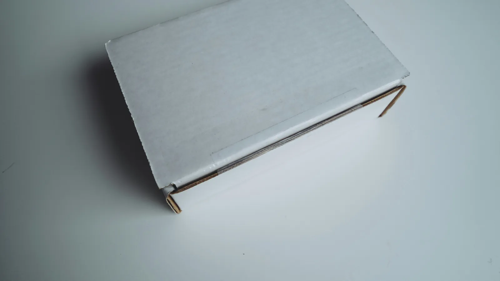 A closed white cardboard shipping box on a pale surface