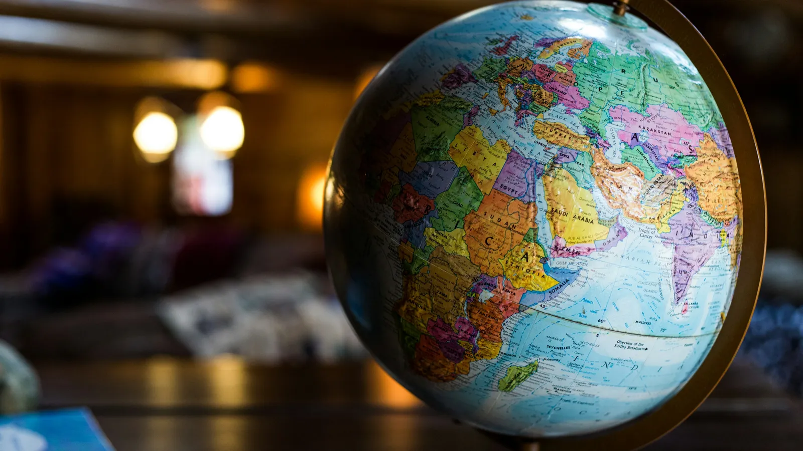 A desk globe in a dimly lit room, turned to show Africa, Europe, the Middle East and South Asia with countries in bright colors.