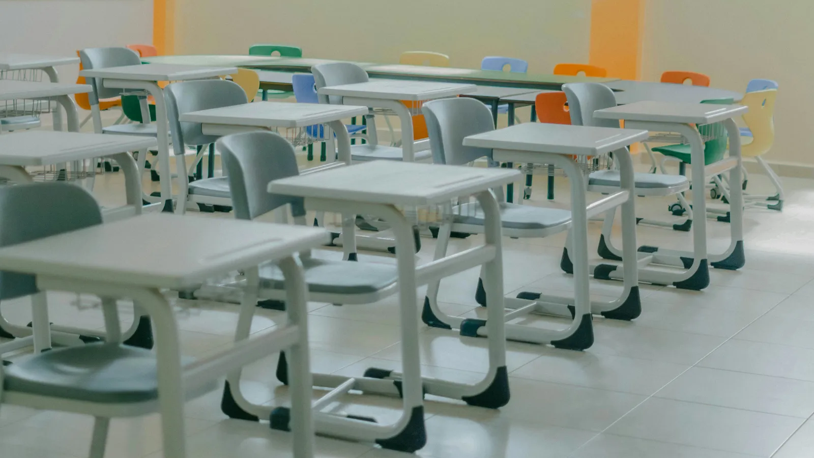 Rows of empty student desks and colorful chairs in a classroom