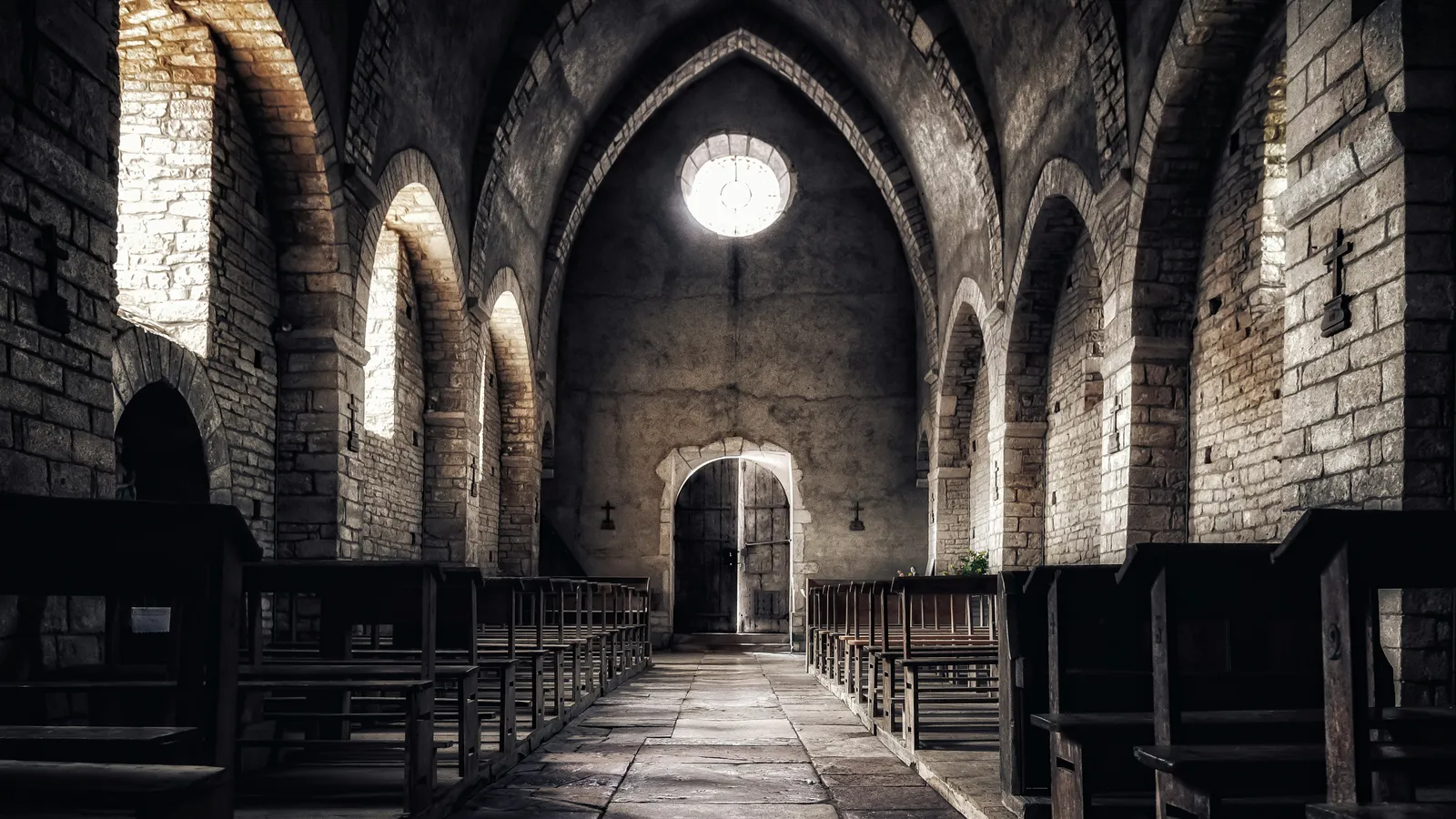 Wooden pews beside a stone aisle in an empty church