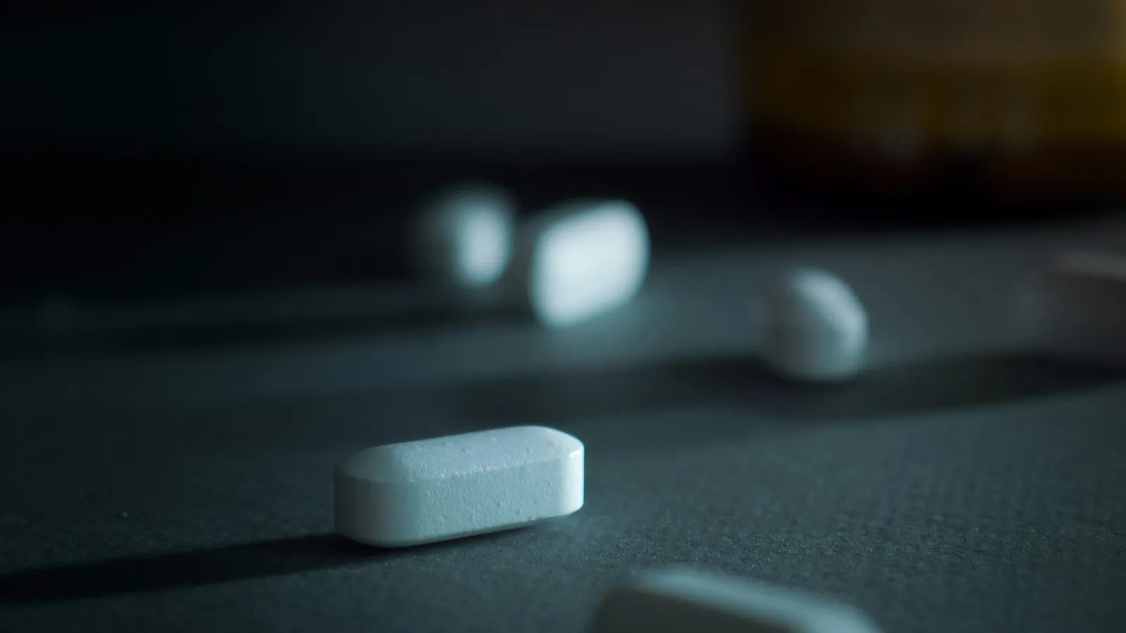 White tablets scattered on a dark gray surface