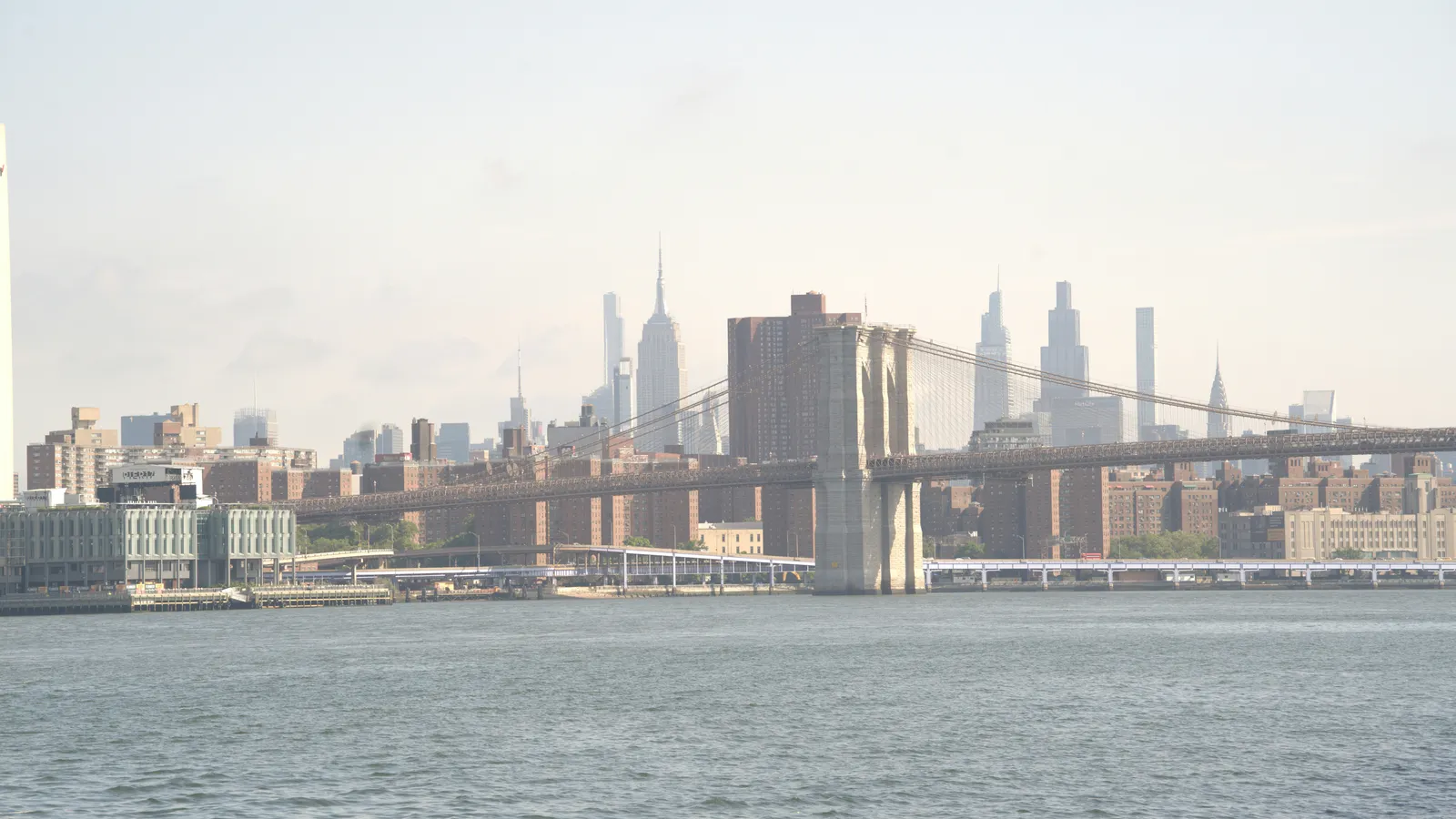 The Brooklyn Bridge over the East River with city buildings behind it