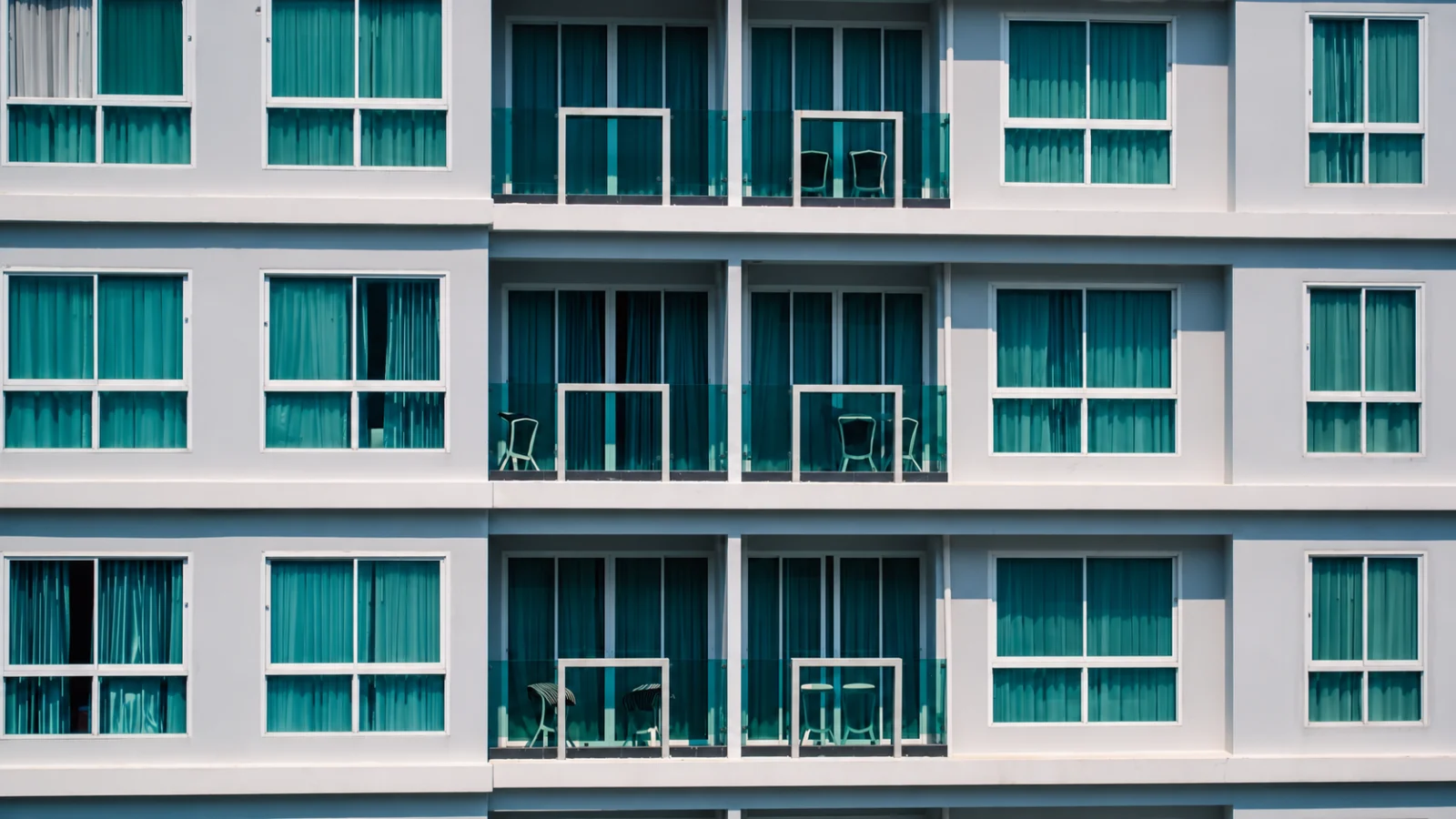 Rows of balconies and windows across a white apartment building facade